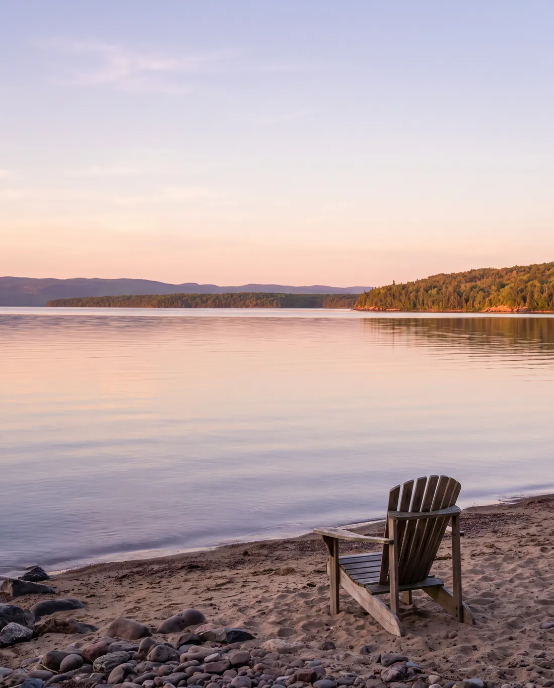 Batchawana Bay on Lake Superior at sunset with a Muskoka chair on the sand
